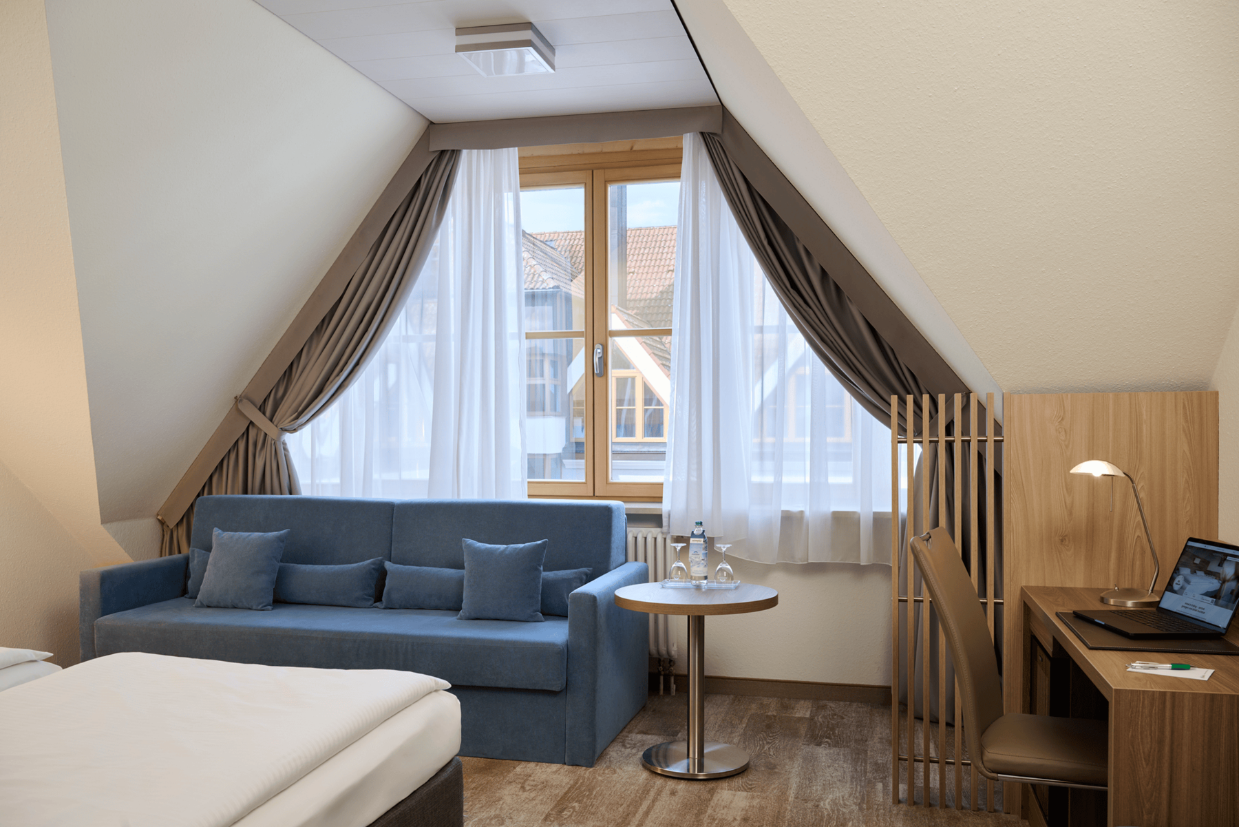 Bright living area of the Family Suite at Hotel Kastanienhof Erding with a comfortable sofa, seating area and practical workspace.