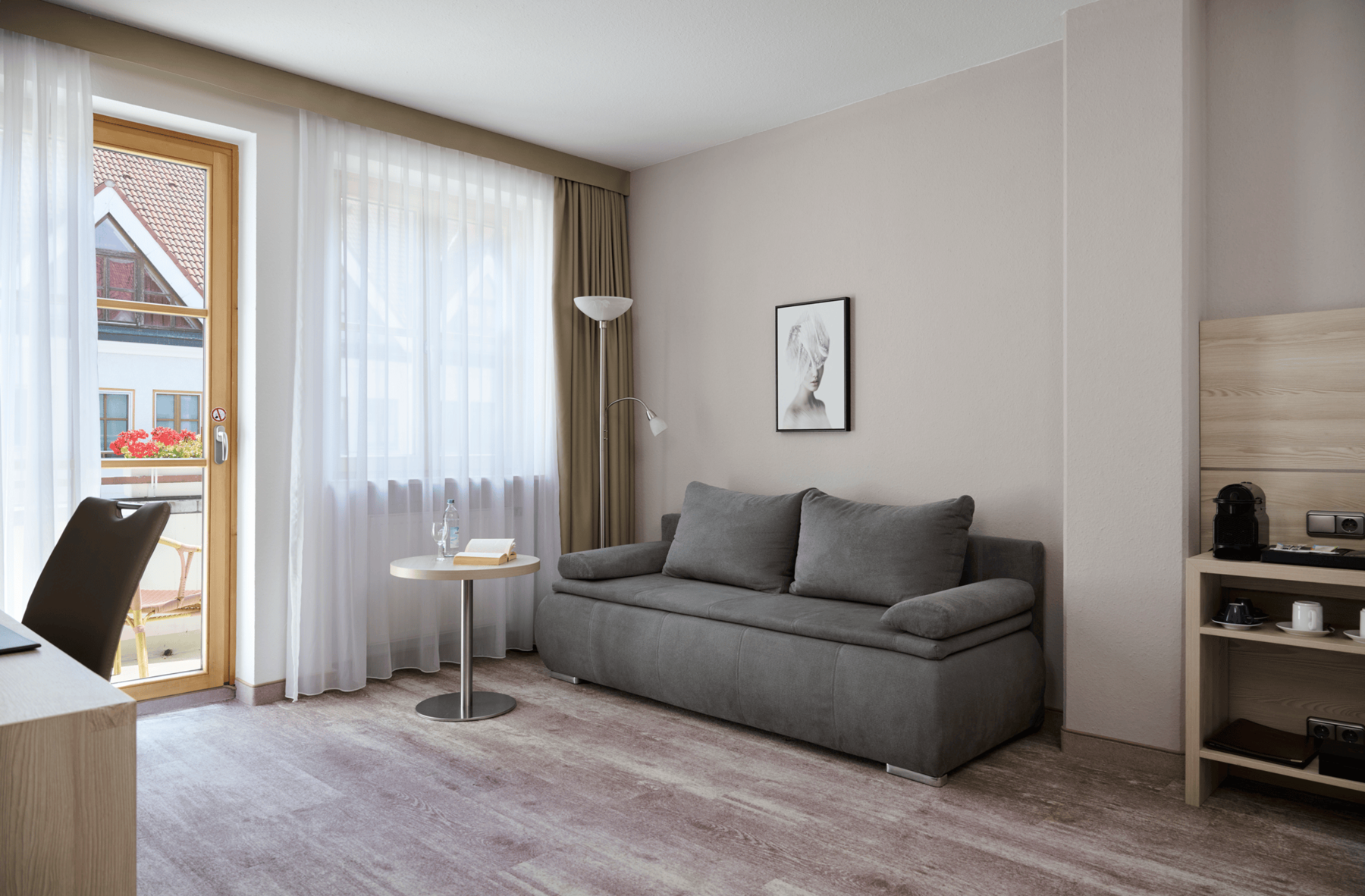 Bright living area of the Junior Suite at Hotel Kastanienhof Erding with a comfortable sofa, seating area and access to the balcony.