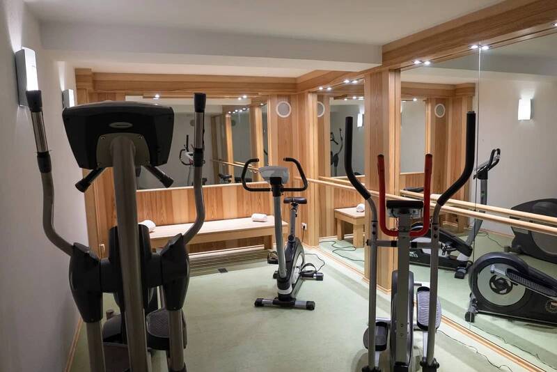 Fitness room at the Hotel Kastanienhof Erding with cross trainers, exercise bikes and mirror wall.