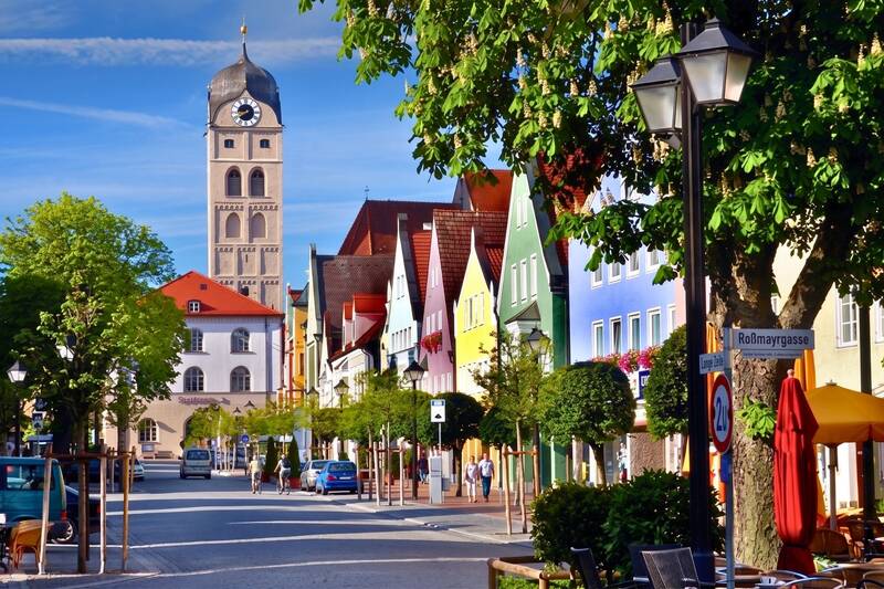 Die historische Altstadt von Erding mit dem Schönen Turm, farbenfrohen Häuserfassaden und gemütlichen Straßencafés an einem sonnigen Tag. Ein idealer Ausgangspunkt für einen Wochenendtrip in Bayern.