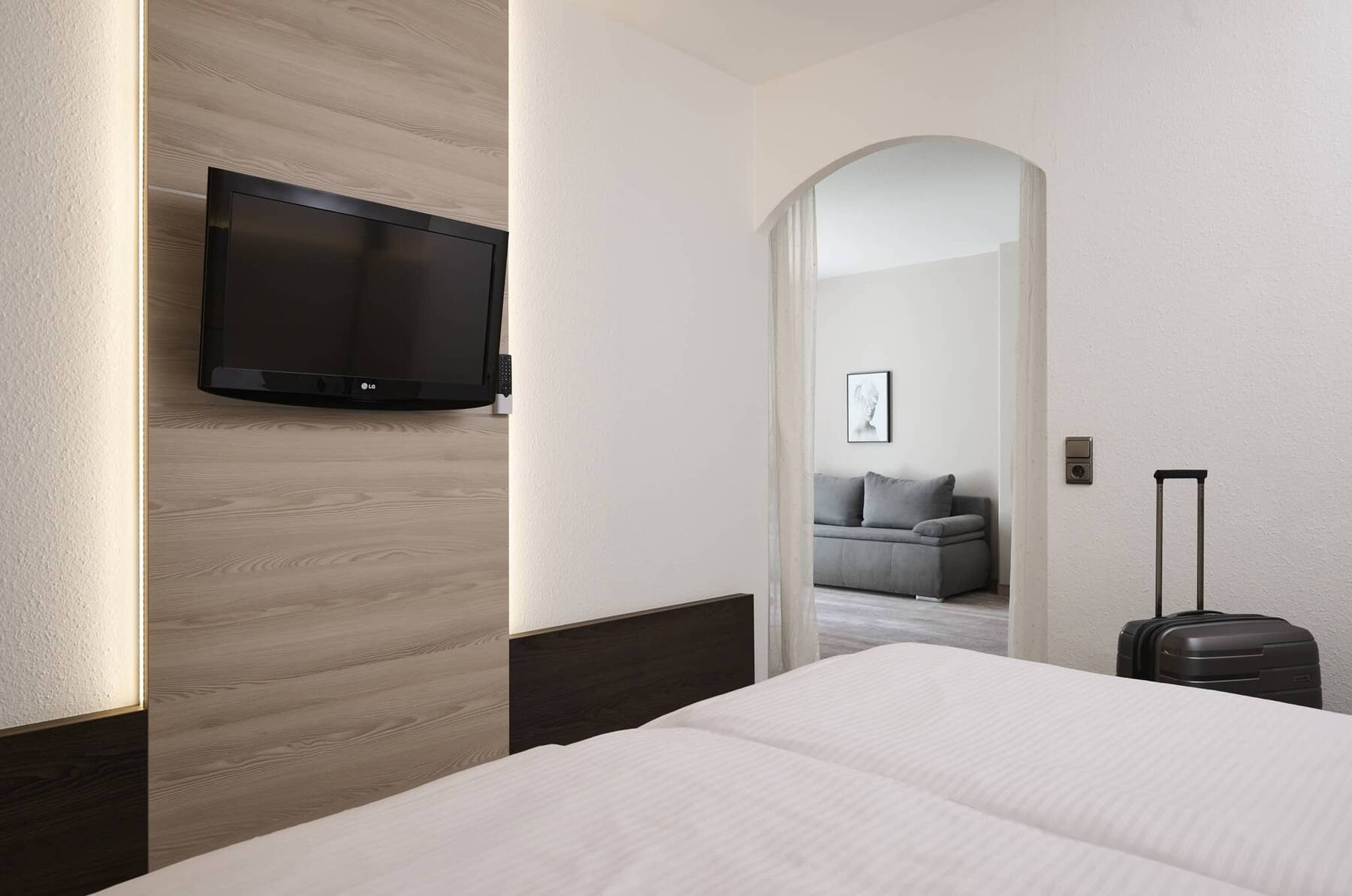 Komfortable Junior Suite im Hotel Kastanienhof Erding mit Schlafbereich, TV und separatem Wohnbereich mit Sofa.