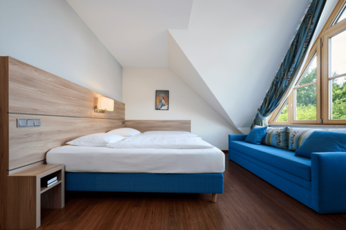 Helles Executive Doppelzimmer im Hotel Kastanienhof Erding mit komfortablem Doppelbett, gemütlicher Sitzecke und großen Fenstern.