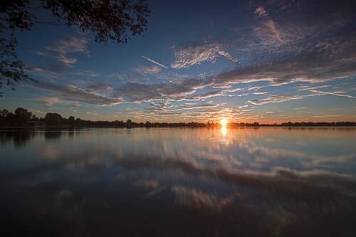 Sonnenuntergang am Kronthaler Weiher in Erding mit Spiegelung der Wolken im Wasser