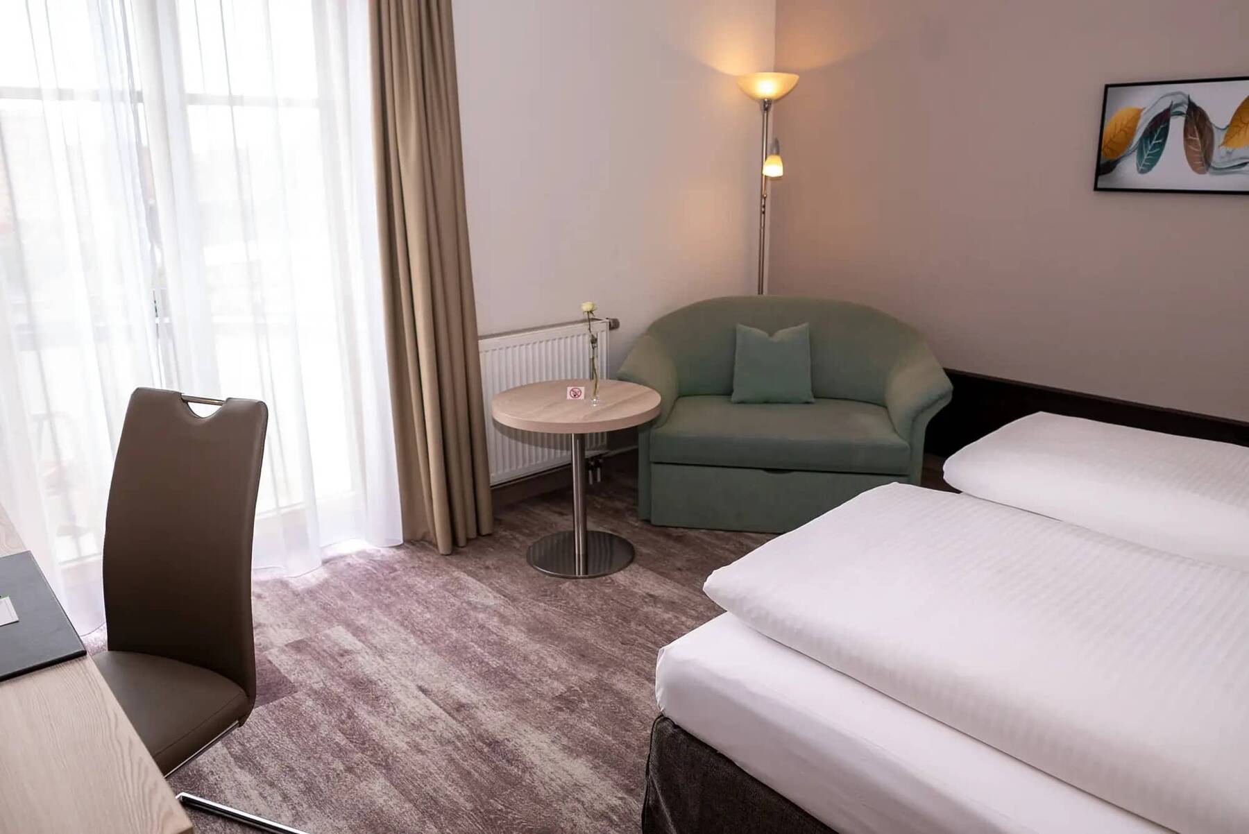 Doppelzimmer im Kastanienhof Schreibtisch und Sitzecke mit einem gemütlichen, grünen Sessel und Beistelltisch.