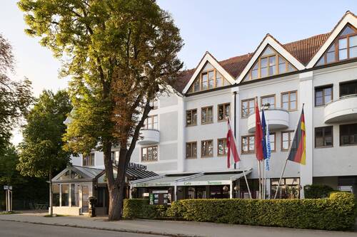 Außenansicht des Hotel Kastanienhof Erding mit heller Fassade, Eingangsbereich, Terrasse und begrüntem Vorplatz.