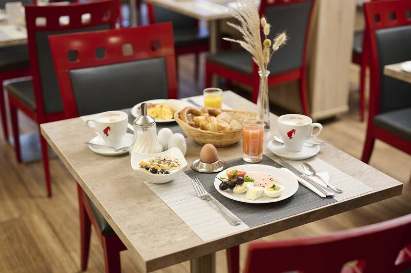 Gedeckter Frühstückstisch im Hotel Kastanienhof Erding mit Kaffee, Säften, Croissants, Müsli, Ei, Käse und frischem Obst.