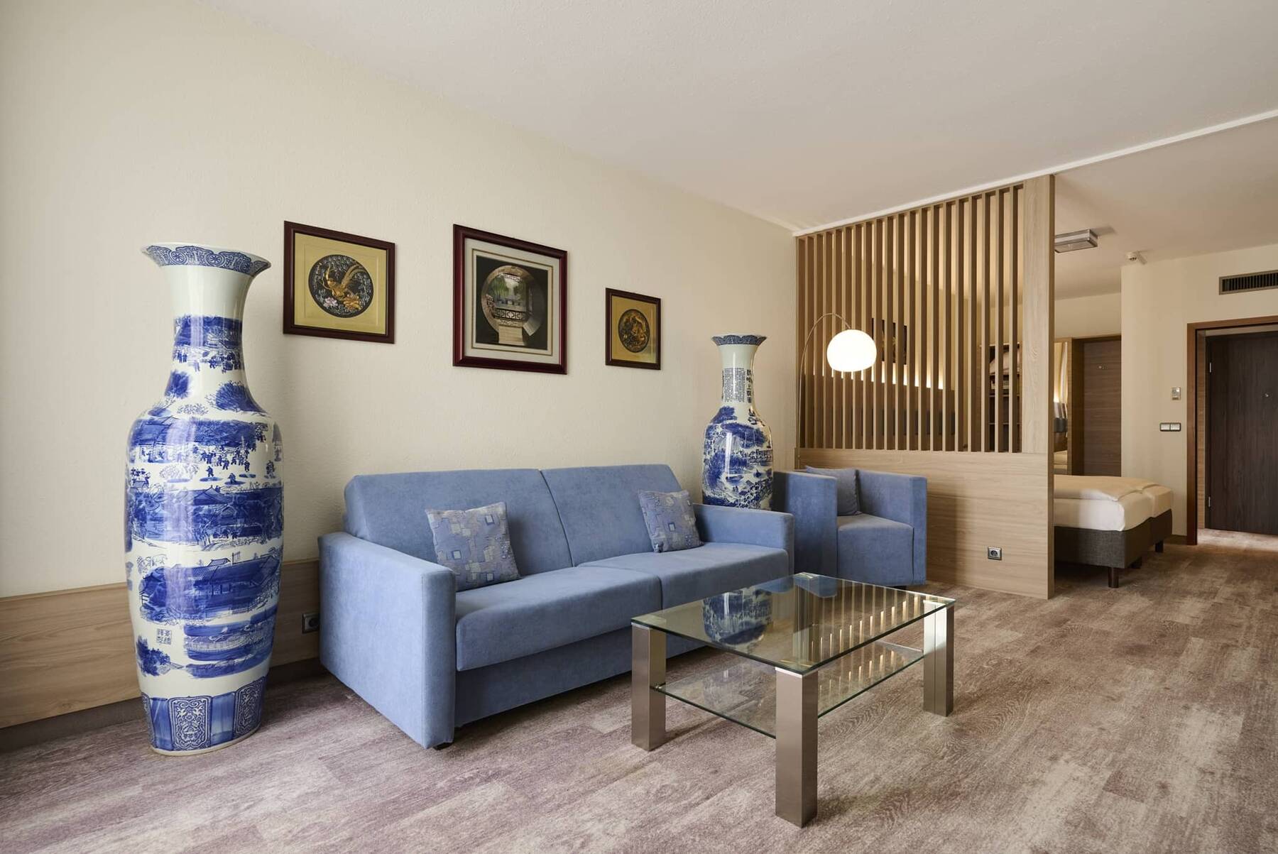 Großzügiger Wohnbereich des Executive Doppelzimmers im Hotel Kastanienhof Erding mit Sofa, Sesseln und separatem Schlafbereich.